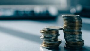 Dva nerovnako vysoké stĺpiky eurových mincí na pracovnom stole